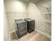 Laundry room featuring modern, front-loading washer and dryer, and metal shelving units for storage at 5576 Rockfern Drive, Lilburn, GA 30047