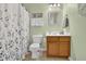 Well-lit bathroom featuring floral shower curtain, decorative mirror, vanity and sink, toilet, and soft green walls at 2480 Sheldon Pl, Cumming, GA 30040