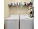 Functional laundry room with white washer and dryer, shelf, and ample storage space for cleaning supplies at 2480 Sheldon Pl, Cumming, GA 30040
