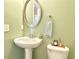 Cozy powder room with a pedestal sink, oval mirror, and neutral-toned walls at 3546 Flycatcher Way, Duluth, GA 30097