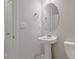 Clean, well-lit half bathroom with a pedestal sink, oval mirror, and white fixtures at 847 Pensive Run, Dacula, GA 30019