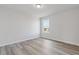A well lit bedroom with wood-look flooring, neutral paint, and a double hung window at 847 Pensive Run, Dacula, GA 30019