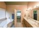 Bright bathroom featuring a soaking tub, double vanity, and view into an adjacent bedroom at 31 Vine Creek Ln, Acworth, GA 30101