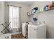 Bright laundry room with modern washer and dryer, storage shelves, and a window with patterned curtains at 336 Elaina Cir, Locust Grove, GA 30248