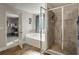 Main bathroom showcasing a soaking tub, glass-enclosed shower, wood-look flooring, and access to the main bedroom at 336 Elaina Cir, Locust Grove, GA 30248