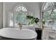 Bright bathroom featuring a soaking tub, large windows with backyard views, and white trim at 703 Cumberland Ne Cir, Atlanta, GA 30306