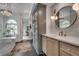 Bathroom featuring modern vanity with round mirror, soaking tub behind glass and accent lighting at 703 Cumberland Ne Cir, Atlanta, GA 30306