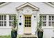 Close-up of the inviting yellow front door with sidelights, potted plants, and decorative accents at 703 Cumberland Ne Cir, Atlanta, GA 30306