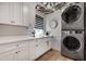 Functional laundry room with white cabinets, countertop space, stacked washer/dryer, and modern fixtures at 703 Cumberland Ne Cir, Atlanta, GA 30306
