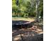 Backyard with a trampoline on a ground covered with leaves, under a lot of tree cover at 865 Cherrydale Ln, Woodstock, GA 30189