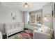 Bright Bedroom featuring a white crib, comfortable chair, window seat, and built-in shelving for storage at 200 Heaton Park Dr, Decatur, GA 30030
