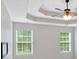 Bright main bedroom featuring a tray ceiling, ceiling fan, and two windows at 57 Craig Meadows Ln, Douglasville, GA 30134