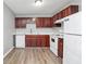 Bright kitchen with white countertops, cherry cabinets, modern appliances, and wood-look flooring at 3711 Daisy Dr, Decatur, GA 30032