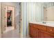 A bathroom featuring striped wallpaper and a wooden vanity, with a partial view of the shower and bedroom beyond at 3907 Fellowship Dr, Buford, GA 30519