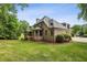 Beautiful backyard with lush green grass, mature trees, and a brick home featuring a covered wooden deck at 9075 Preston Ln, Suwanee, GA 30024