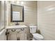 Powder room featuring a decorative mirror, marbled vanity, wall paneling, and neutral color palette at 9075 Preston Ln, Suwanee, GA 30024