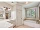 Bright bathroom with tile flooring, a soaking tub, vanity, and window bringing in natural light at 9075 Preston Ln, Suwanee, GA 30024