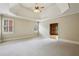 Spacious bedroom featuring a tray ceiling, neutral carpet and natural light at 9075 Preston Ln, Suwanee, GA 30024