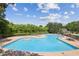Aerial view of community pool featuring lounge chairs, tables, and lush green trees surrounding the area at 9075 Preston Ln, Suwanee, GA 30024