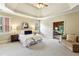 Spacious main bedroom with sitting area, tray ceiling, shutters, and view to the office at 9075 Preston Ln, Suwanee, GA 30024