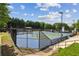 Active community tennis courts with multiple players and perimeter fencing under a bright, partly cloudy sky at 9075 Preston Ln, Suwanee, GA 30024