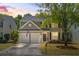 Charming two-story home featuring a two-car garage, manicured lawn, and mature tree during a sunset at 512 Watercress Dr, Woodstock, GA 30188