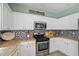 Bright kitchen with stainless steel appliances, white cabinets and stylish backsplash at 512 Watercress Dr, Woodstock, GA 30188