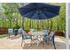 Outdoor patio featuring a dining table, chairs, and a large umbrella, surrounded by lush greenery at 512 Watercress Dr, Woodstock, GA 30188