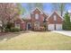 Charming two-story brick home featuring a well-manicured lawn, blooming flowers, and a two-car garage at 625 Park Creek Trce, Alpharetta, GA 30005