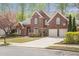 Brick two-story home with well-maintained front lawn and garden featuring mature trees and a two car garage at 625 Park Creek Trce, Alpharetta, GA 30005