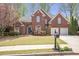 Brick two-story home with well-maintained front lawn and garden featuring mature trees and a two car garage at 625 Park Creek Trce, Alpharetta, GA 30005