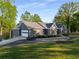 Well-maintained single-story home featuring a lush green lawn, dark siding, wooden shutters, and attached garages at 6477 Old Shadburn Ferry Rd, Buford, GA 30518