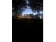 A home with lights on in the evening, surrounded by green grass and mature trees at 6477 Old Shadburn Ferry Rd, Buford, GA 30518