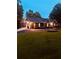 Well-maintained single-story home with lush front lawn, dark siding and attached garages at dusk at 6477 Old Shadburn Ferry Rd, Buford, GA 30518