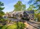 Charming home featuring gray painted brick, shutters, mature trees, and a driveway leading to a golf cart at 6477 Old Shadburn Ferry Rd, Buford, GA 30518