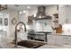 Close up of the gourmet kitchen with stainless steel range, pot filler, and open shelving at 6477 Old Shadburn Ferry Rd, Buford, GA 30518