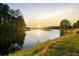 Tranquil lake view at sunset with lush green grass in the foreground at 6477 Old Shadburn Ferry Rd, Buford, GA 30518