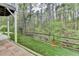 View of a backyard with a wooden fence and a treeline beyond the grassy area at 3045 Hartridge Dr, Johns Creek, GA 30022