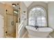 Bright bathroom with a soaking tub beneath a large window and separate glass-enclosed shower at 3045 Hartridge Dr, Johns Creek, GA 30022
