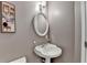 Powder room with pedestal sink, oval mirror, decorative picture and grey wall at 3045 Hartridge Dr, Johns Creek, GA 30022