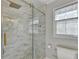 Close up of glass shower with gold trim, marble walls and pebbled floor, plus a window at 3045 Hartridge Dr, Johns Creek, GA 30022