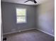 Minimalist bedroom featuring neutral carpet, light gray paint, and a window overlooking greenery at 8977 Teal Ln, Jonesboro, GA 30236