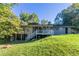 Grassy backyard featuring a charming brick home with a screened porch and stairway at 8596 Timberlane Dr, Douglasville, GA 30134