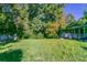 A grassy backyard featuring a charming brick home with a screened porch surrounded by mature trees at 8596 Timberlane Dr, Douglasville, GA 30134