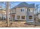 Rear of home shows gray siding, a covered patio area, and plentiful windows, partially obscured by trees at 909 Sunny Meadows Lane, Marietta, GA 30062