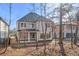 The home's rear facade is showcased behind trees, revealing gray siding, multiple windows, and a covered patio at 909 Sunny Meadows Lane, Marietta, GA 30062