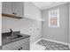 Functional laundry room with gray cabinets, sink, decorative flooring, and bright window at 909 Sunny Meadows Lane, Marietta, GA 30062