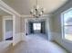 Bright dining room featuring large windows, neutral paint, plush carpet, and modern chandelier at 556 Paden Ridge Way, Lawrenceville, GA 30044