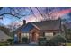Charming brick home featuring an arched doorway and complemented by manicured landscaping at twilight at 958 Winburn Dr, Atlanta, GA 30344