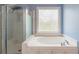 Bathroom with large tub, clear glass shower, and frosted window, allowing ample natural light at 539 Riverbirch Trce, Stone Mountain, GA 30087